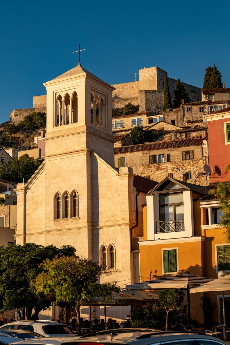 A scenic view of a historic church in Šibenik during sunset, showcasing vibrant architecture.