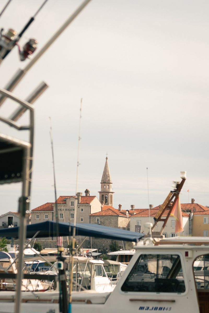 Explore the charming harbor of Budva with its iconic towers and townscape framed by boats.