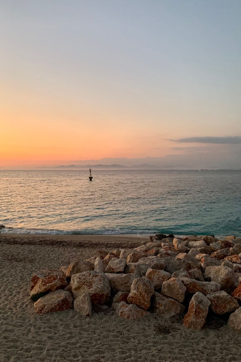 Tranquil sunset over the Ionian Sea with rocky shoreline and calm waters in Greece.