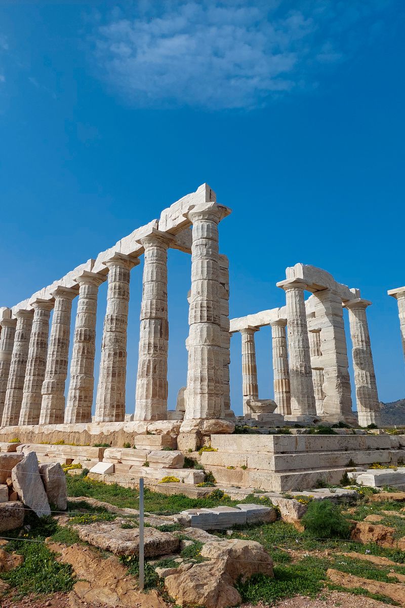 The ancient Temple of Poseidon at Cape Sounion under a bright blue sky, a renowned Greek landmark.