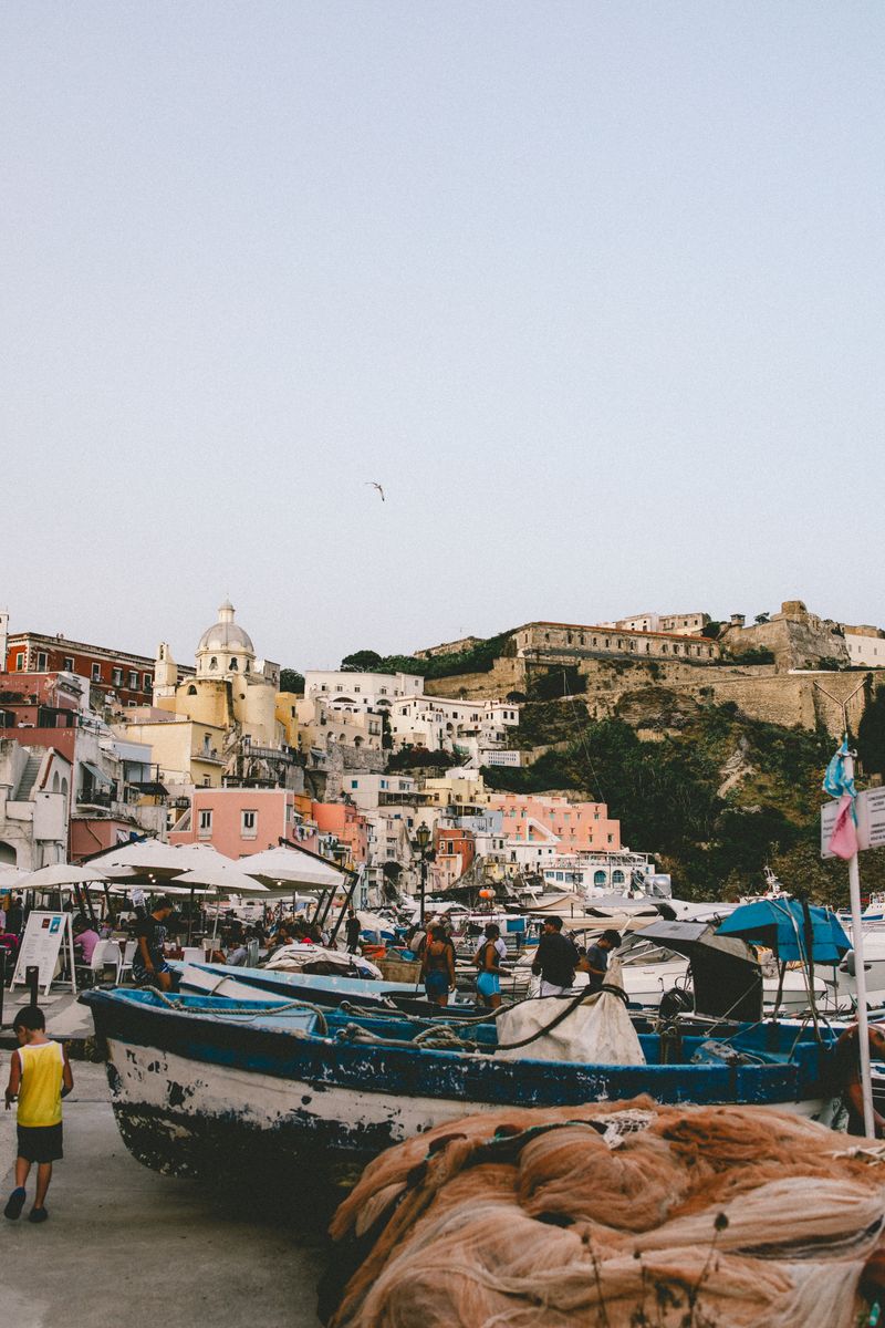 Explore the picturesque fishing harbor in Procida, Italy, with colorful boats and historic architecture.