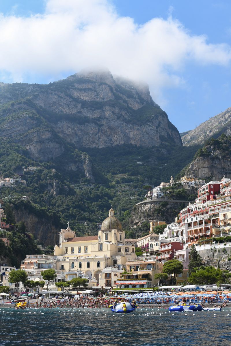Stunning vertical view of Positano's waterfront with mountains and vibrant beach life.
