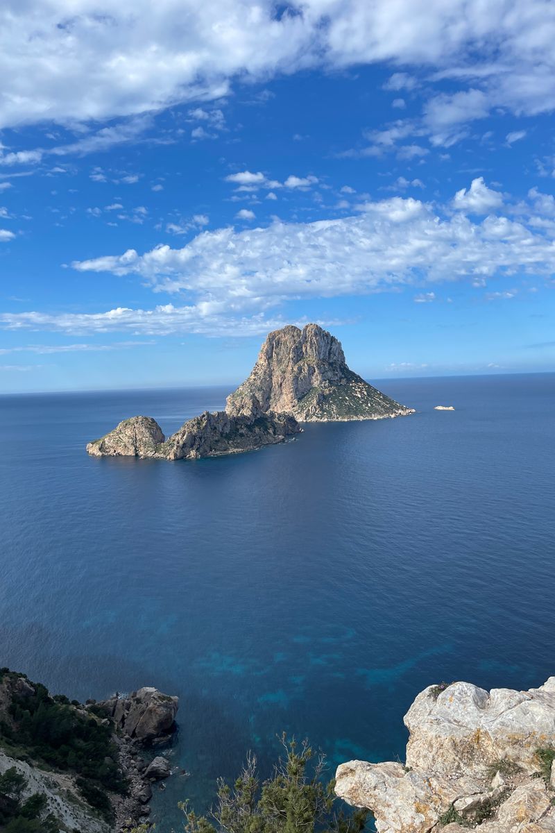 A breathtaking view of the iconic Es Vedrà island off the coast of Ibiza, under a clear blue sky.